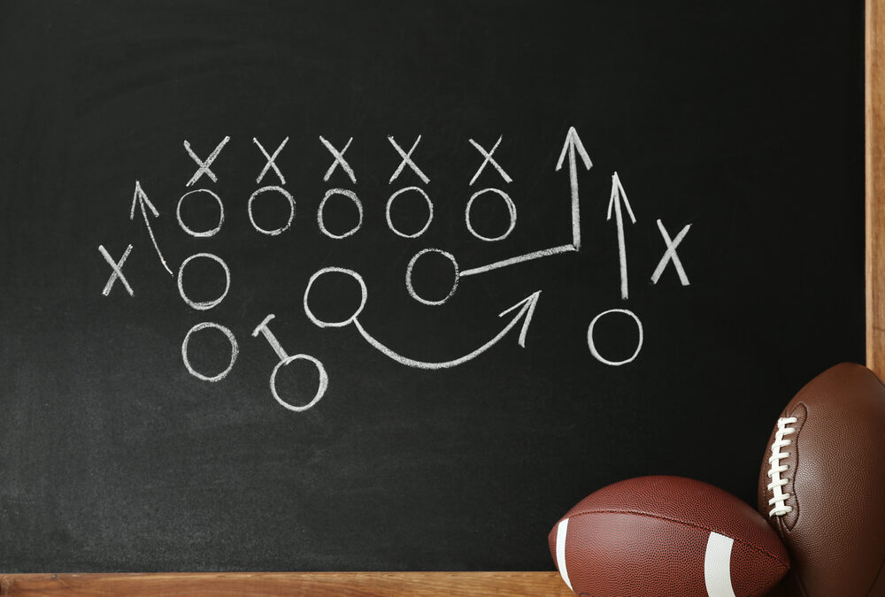 footballs near chalkboard with football playbook
