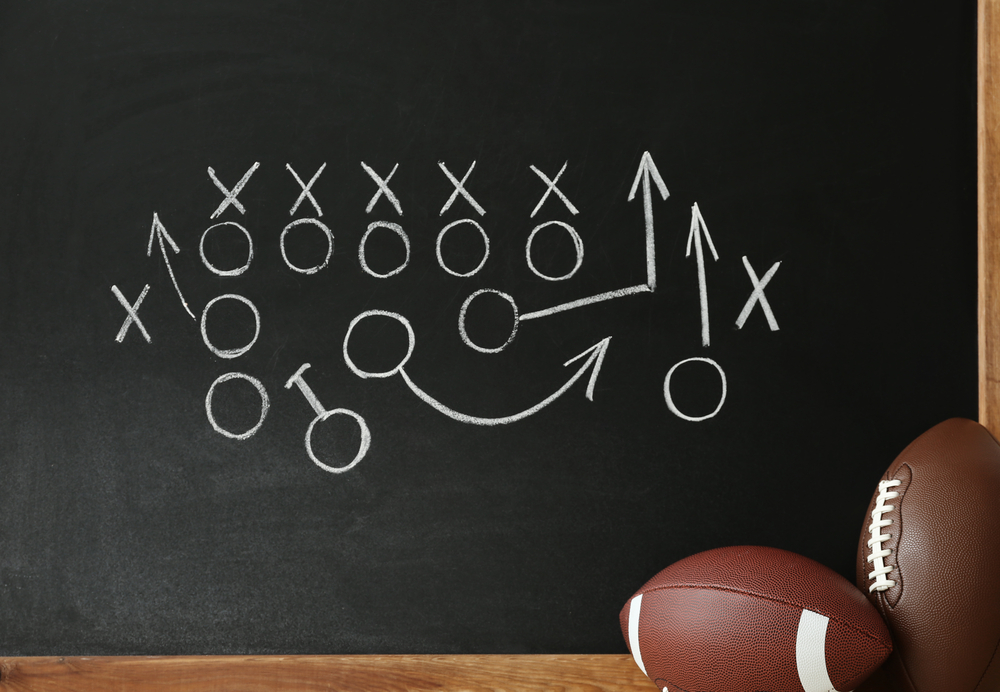 footballs near chalkboard with football playbook